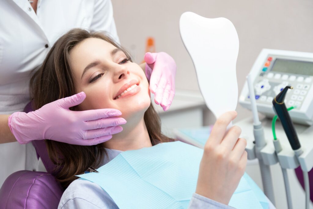 Patient smiling at reflection as with dentist standing behind her